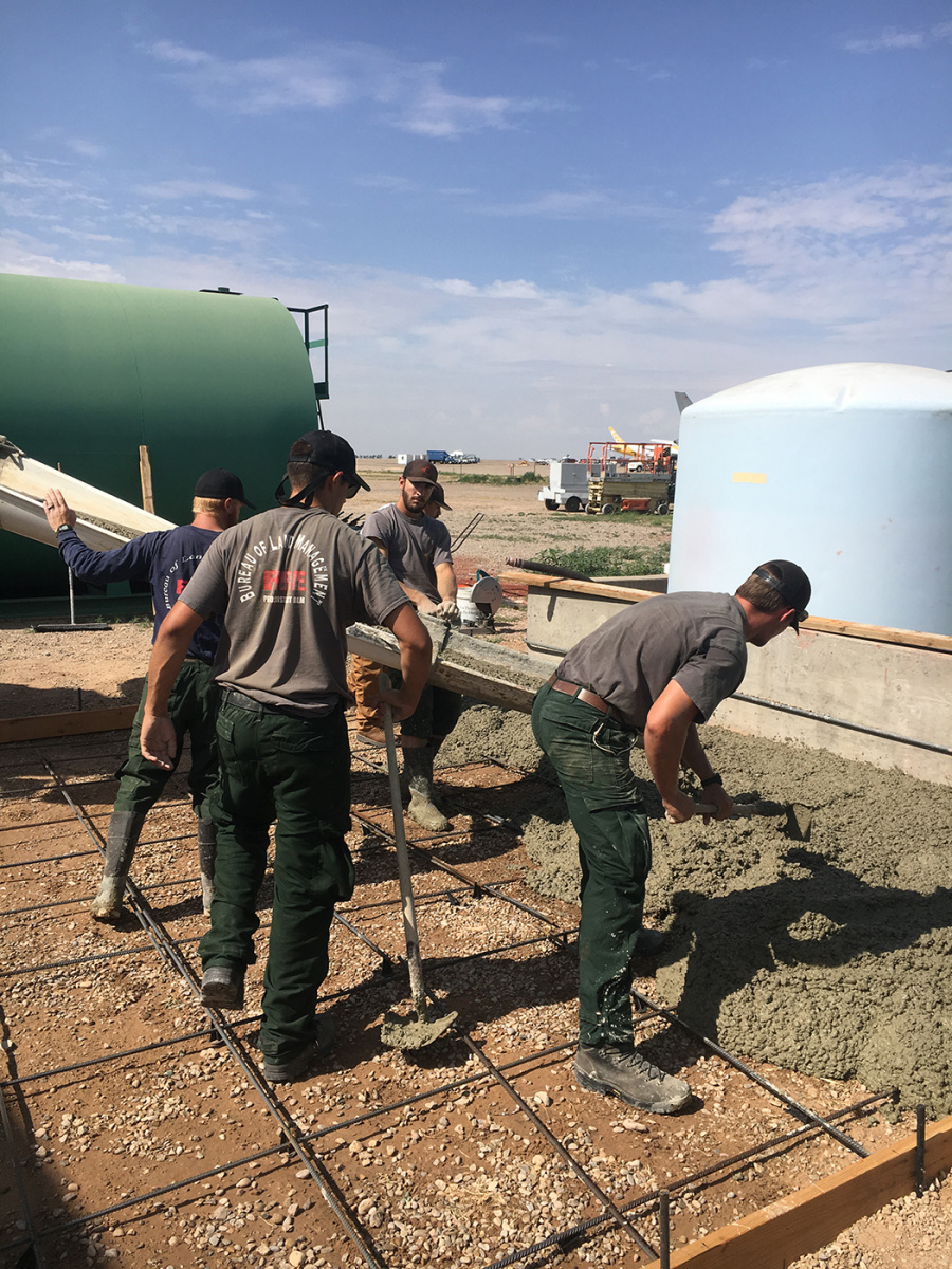 Pecos District fire crew members pour concrete slab to convert retardant from liquid concentrate to powder.