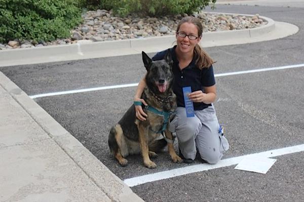 Tracy kneeling with her dog in a parking lot.