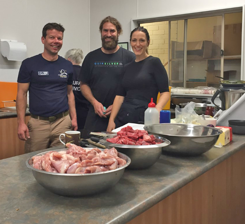 Three people standing behind raw food on a table