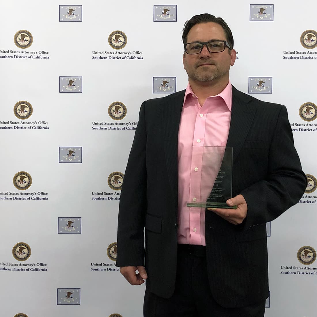 Special Agent Brad K is standing with his award.