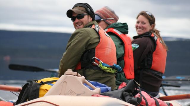 Three people wearing life vests in a raft