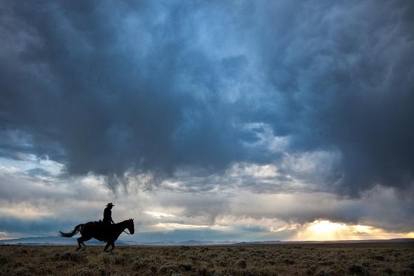 Pony Express Trail west of Casper WY.  Bob says: "The vast sagebrush steppe of WY was a perfect place to capture an image of the young men who rode for the Pony Express. In this image, a young woman, a member of the Pony Express Re-Ride group, helped us re-enact the Pony Express Ride." (Photo by Bob Wick)