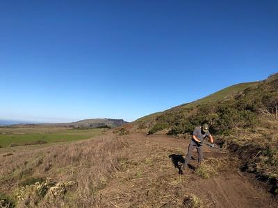 A person doing some work on a trail on a mountain.