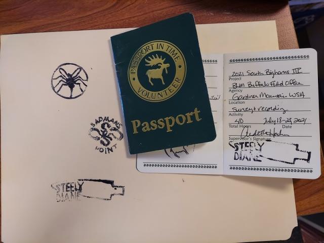 up-close view of "Passport in Time" passports- a small blue book with "Passport in Time" written on it. Another passport is open so that the fields that are filled in can be seen.