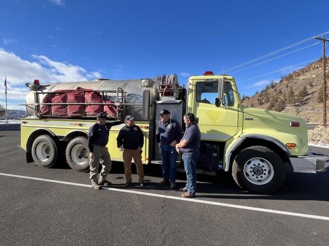 Wheeler County Fire and Rescue RFPA firefighters discuss fires from the past summer in front of the water tender