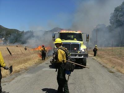 Fire engine with firefighters and a controlled burn.