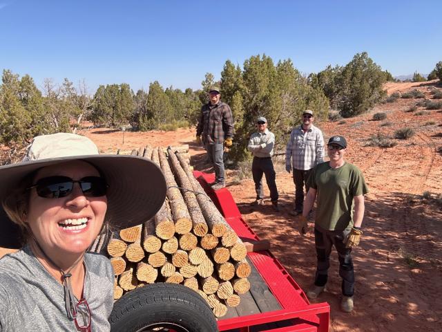 A group poses with a load of posts for new buck-and-rail fencing