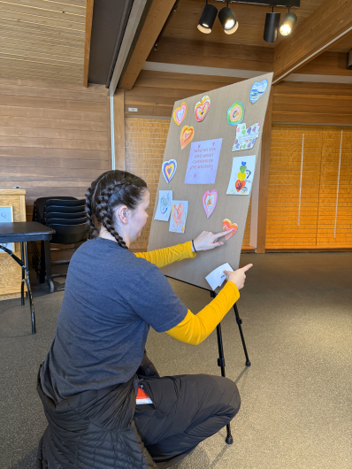 a young woman pastes a painted heart onto a poster