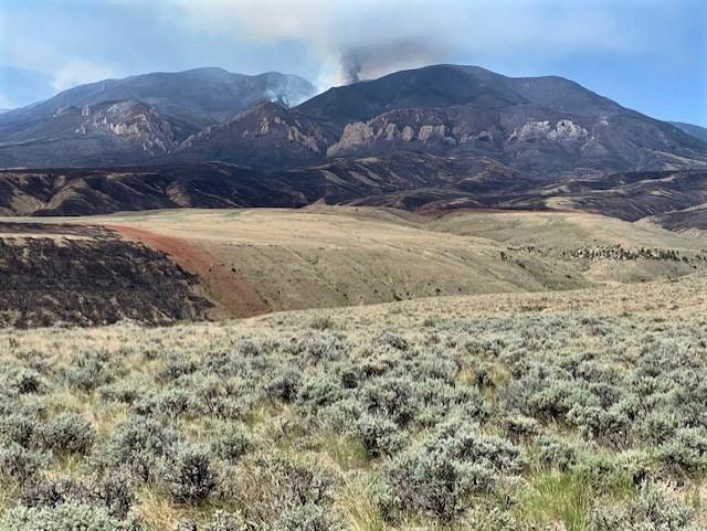 a photo of smoke rising over a mountain and public lands burned by the Robertson Draw Fire