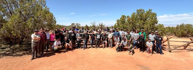 Group photo of volunteers and partners in front of buck-and-rail fencing