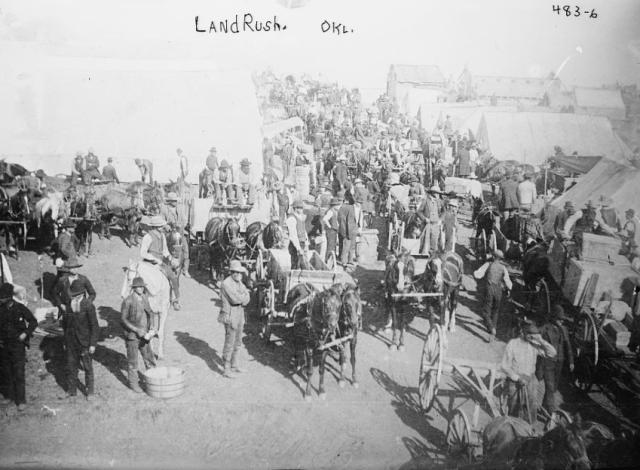 Crowds of people with horse-drawn wagons near tents and buildings in Oklahoma