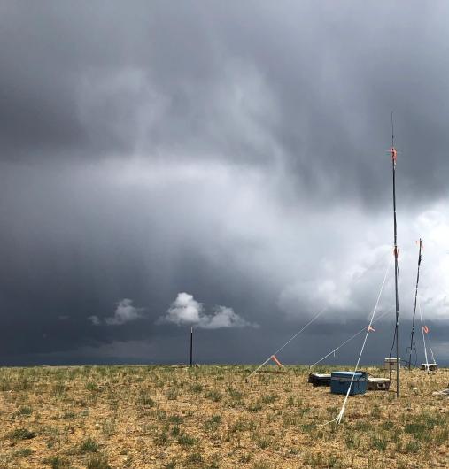 A metal structure with rods extending upwards stands on a flat landscape under a stormy sky