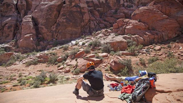 One person sits while another lies back on a rock. The canyon walls looming in front of them. 