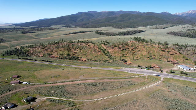 This is Poncha Pass. The roadway and power lines in this photo make up the main transportation and energy transmission corridor serving the San Luis Valley.  The land pictured here straddles two counties. It includes both private and public land, which falls under the jurisdictions of both the Bureau of Land Management and the U.S. Forest Service. Photo by Amy Bulger, courtesy of the Colorado State Forest Service