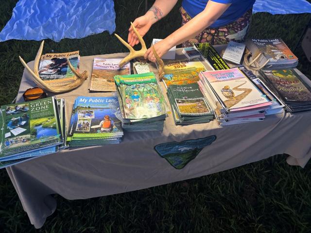 A table displays various nature guides and brochures, including antlers, promoting public lands and outdoor activities.