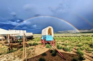 Rainbow arching over covered wagon in bright sun