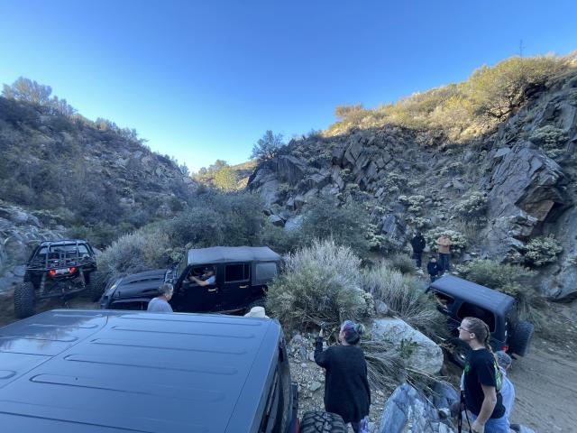 People ride in OHVs and Jeeps in a rocky landscape