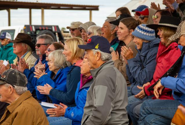 A large audience claps after a demonstration of wild horses and burros