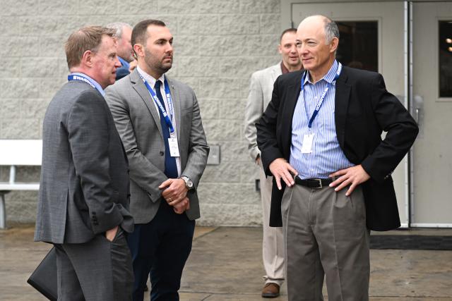 A group of four men in business attire engaged in conversation outside a building, showcasing a professional setting.