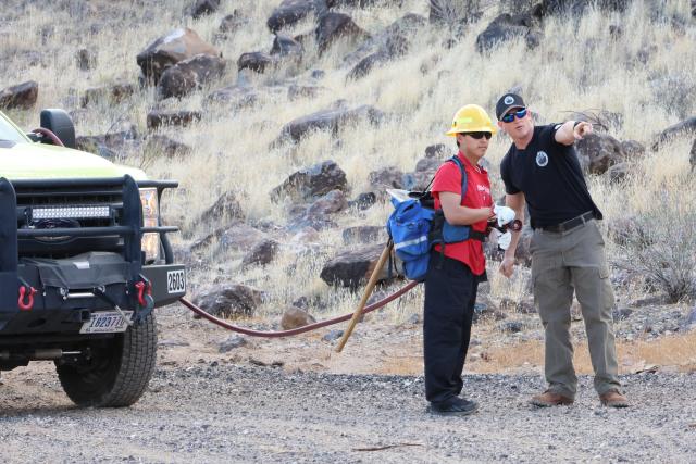 A firefighter points next to a student holding a fire hose.