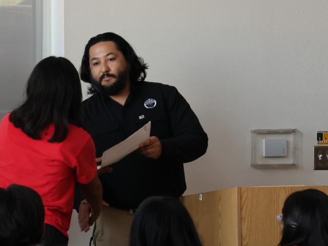 a firefighter presents a certificate to a high school student