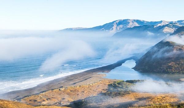 Fog descends on a mountainous beach.