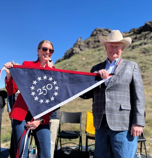 Image of two people holding a commemorative America 250 anniversary banner