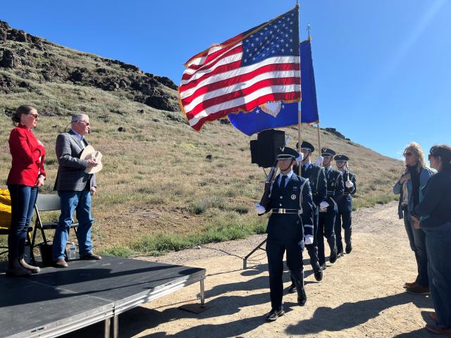 Uniformed service members marching holding the American flag and state of Idaho flag.