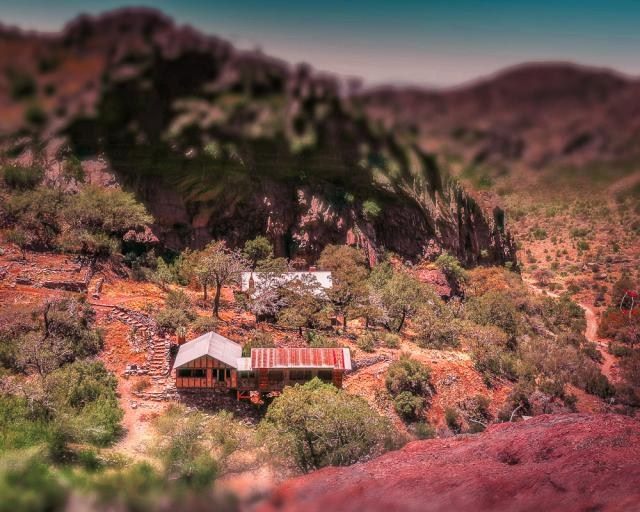 A group of abandoned buildings at the base of a cliff.