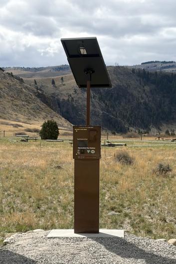 A photo of a credit card enabled kiosk in a recreation area with mountains and trees in the background