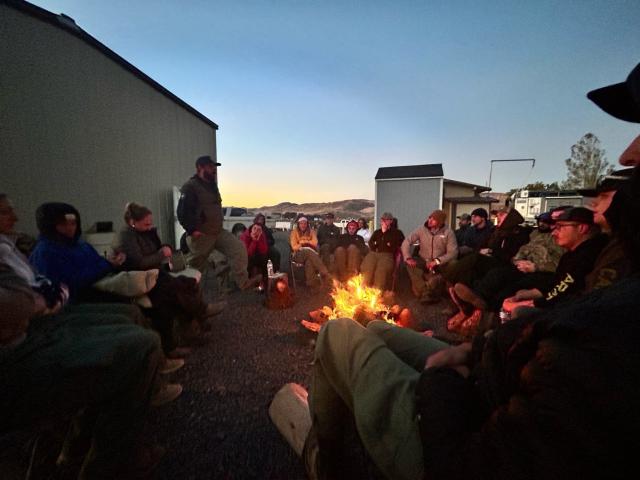student firefighters gathered around a campfire at night