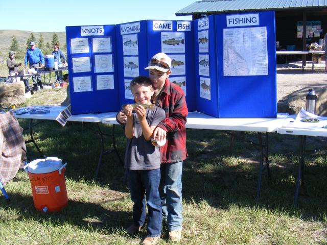 Two kids pose for a photo with their catch of the day, fish.