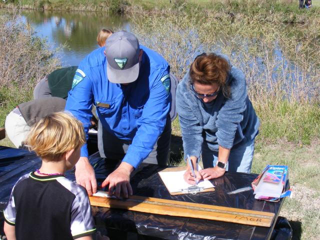 BLM staff help youth at the weigh in table with their fish.