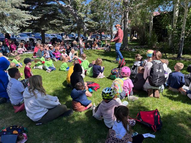 children gather around BLM employee outside for a story time event in WY
