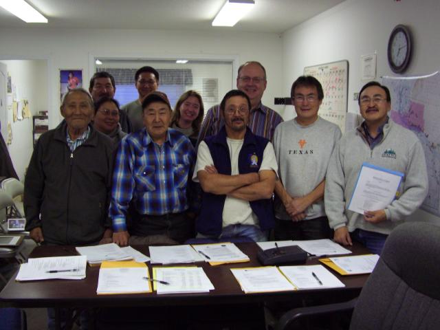 The leaders of the Native Village of Mountain Village (Calista Region) standing behind a table with their signed patent documents spread out on it. 