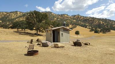 A campsite and restroom in dry hills