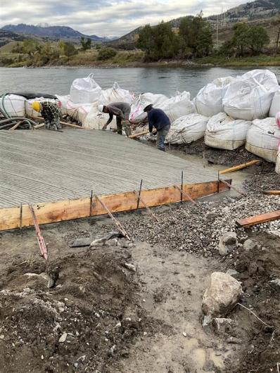 Two workers are working on constructing the new boat ramp 