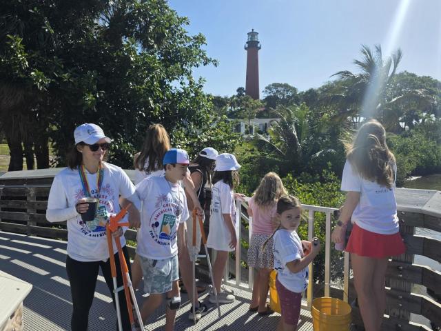 A group of volunteers looks out toward the Jupiter Inlet Lighthouse from the pedestrian pier, enjoying panoramic views of the Jupiter Inlet and Loxahatchee River.