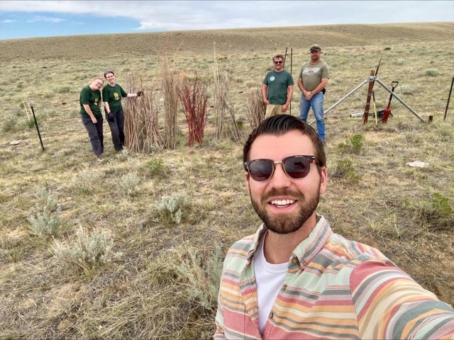 A group of people take a selfie on a grassy plain 