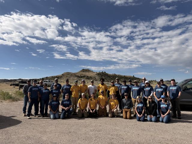 a group of people stand together under a cloudy blue sky