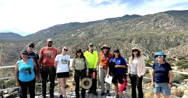 Group of people standing on a platform with mountains and desert landscape in the background