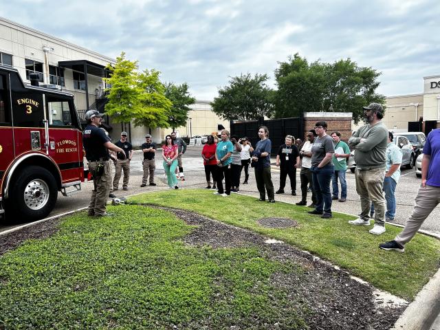 Team members gather outside as firefighters explain key fire‑safety procedures and emergency response tips.