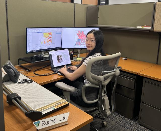 A Graphic Information System Specialist sits are her desk with the mapping data for the Desert Tortoise caution sign project.