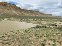A brown reservoir beneath rocky cliffs