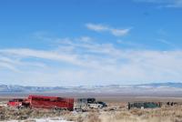 Pick-up trucks with trailers and horses on the range. 