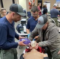 Two people use medical equipment on a medical mannequin. 