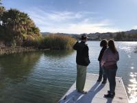 Three people stand on a boat launch