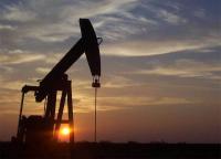 Silhouette of an oil and gas pump jack at sunset