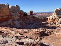 Swirling red and white sandstone formations under a clear blue sky in a desert landscape.