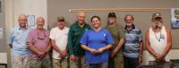 Seven fisheries volunteers stand together with the program leader in a meeting room during a volunteer appreciation event.